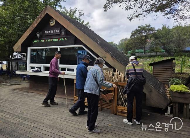 등산객들이 광교산 등산 안내소 앞에 있는 지팡이를 고르고 있다.
