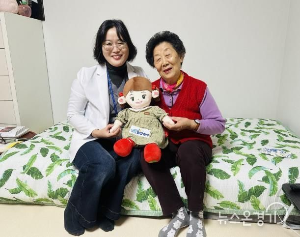 화성시동탄보건소 관계자와 독거 어르신이 AI 돌봄로봇 ‘효돌이’를 함께 들고 환하게 웃고 있다